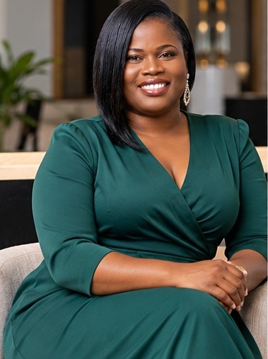 Cherline Daniel seated in a green dress, smiling